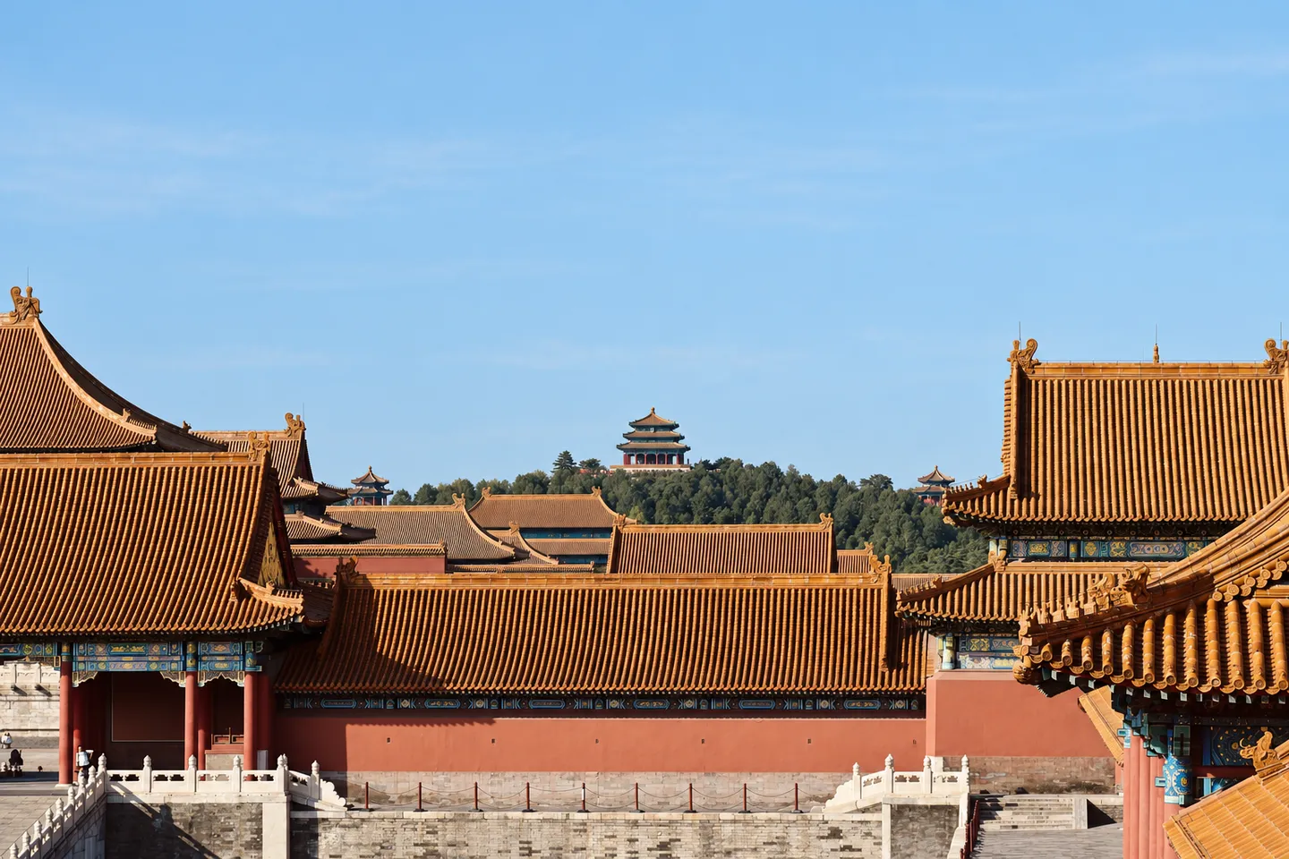 Orange Forbidden City rooftops with a Jingshan pavilion in the distance