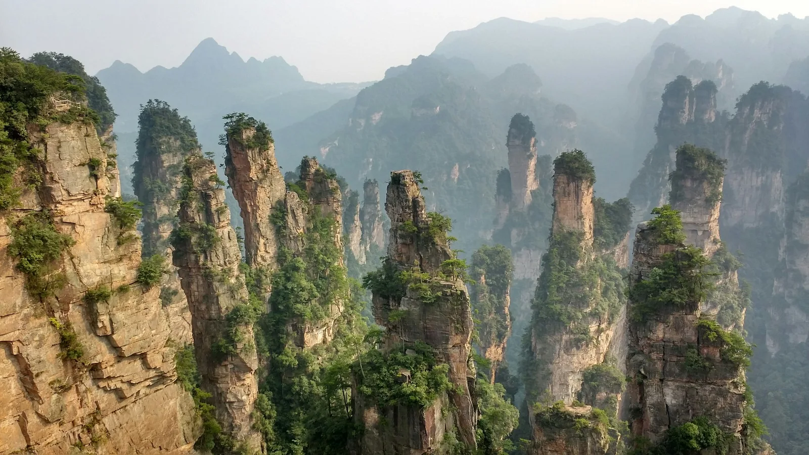 Narrow sandstone pillars rising above a forested valley in Zhangjiajie